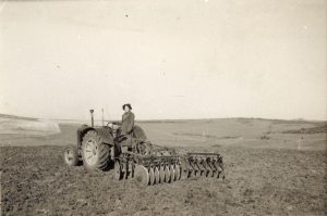 A land girl operating a tractor
